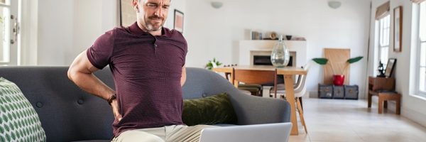 mature-man-stretching-back-while-working-at-home.jpg