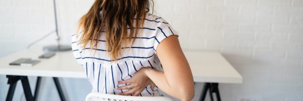 overworked-woman-with-back-pain-in-office-with-bad-posture